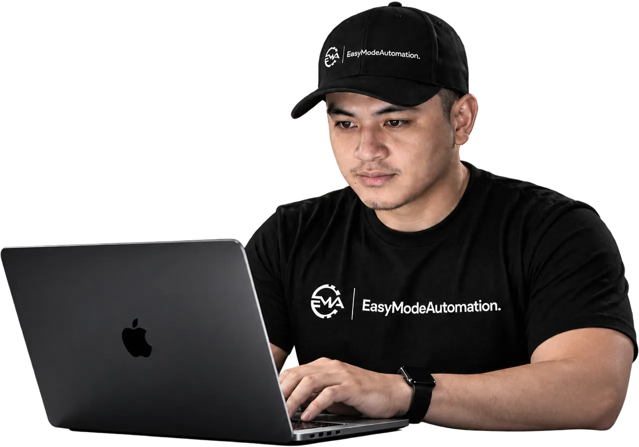 John Dale Del Mundo working at a laptop, in an EasyModeAutomation cap and T-shirt